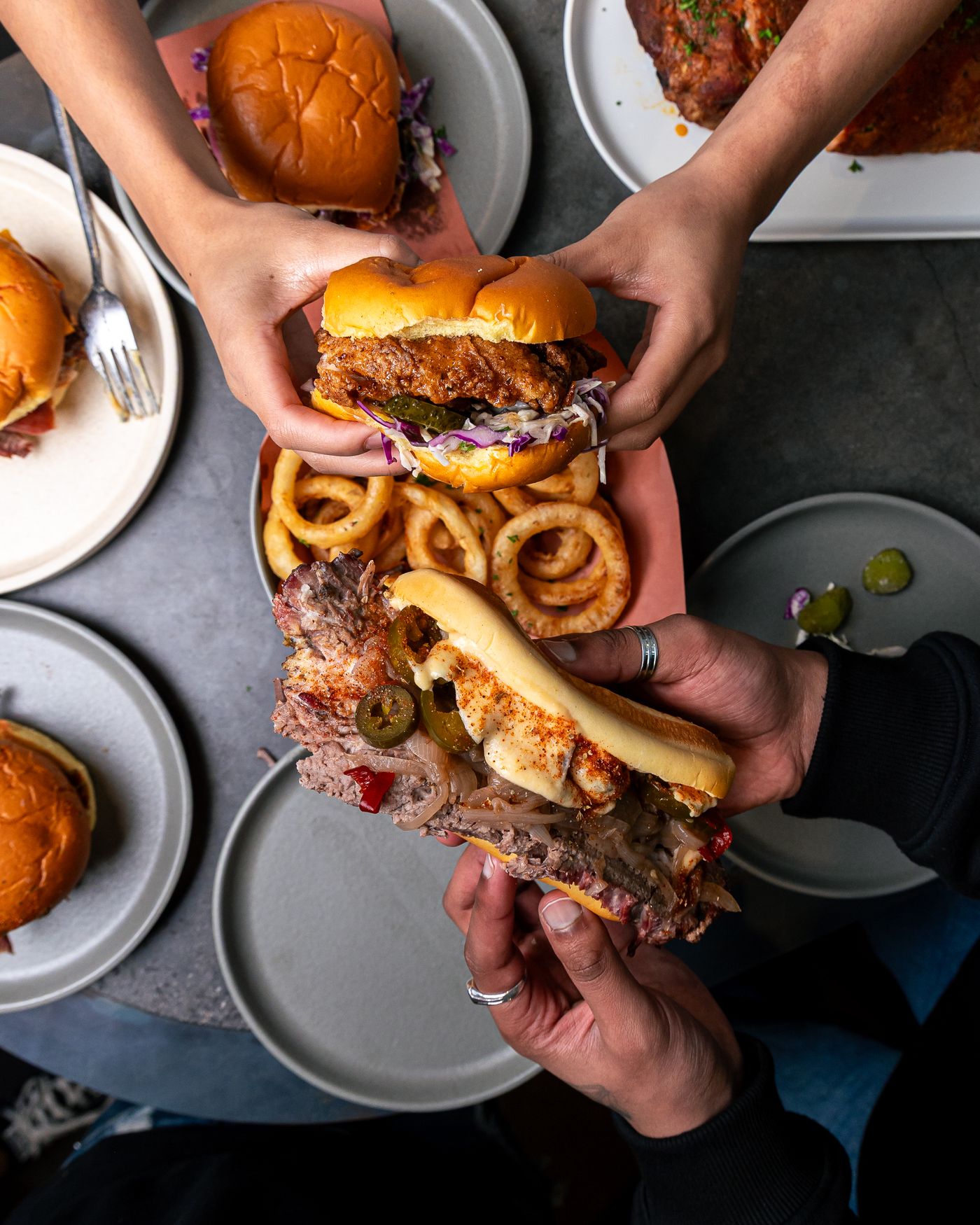 Friends sharing burgers, onion rings and smoked meats at Smokey Soul