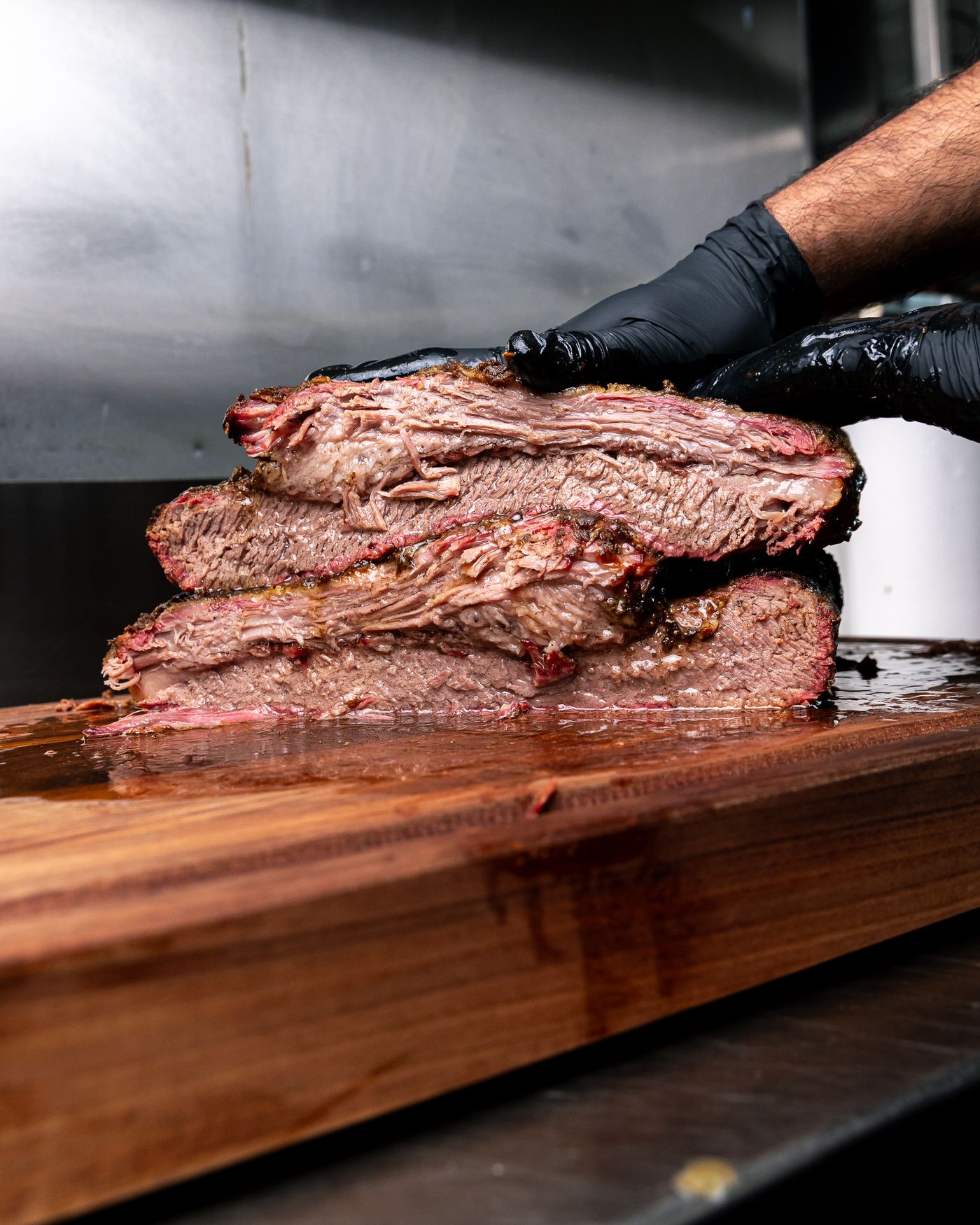 Thick slices of smoked brisket stacked on a wooden board