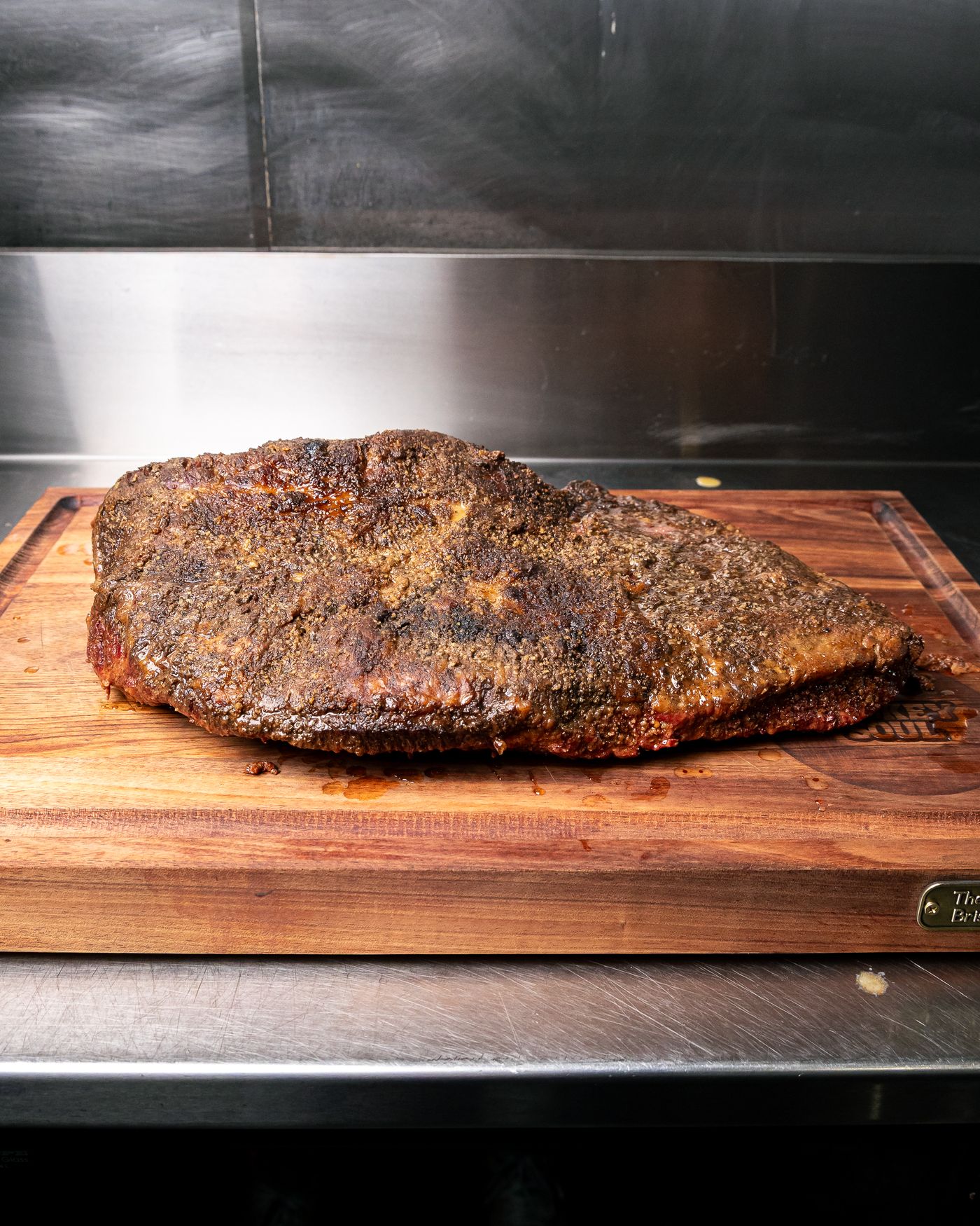 Whole smoked brisket with a peppery bark on a cutting board
